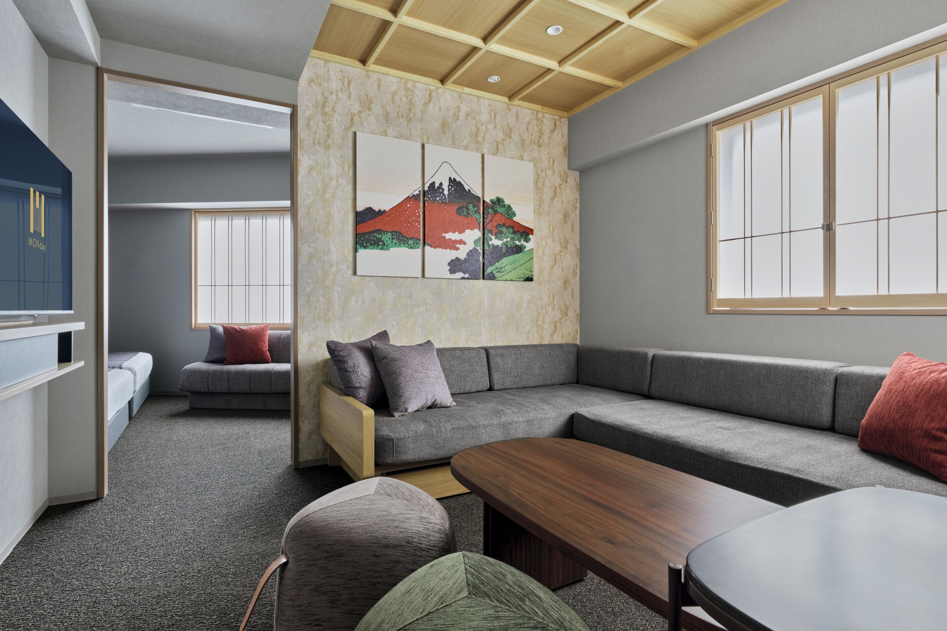A modern living room with a sectional sofa, a wooden coffee table, and a wall-mounted painting of a mountain.