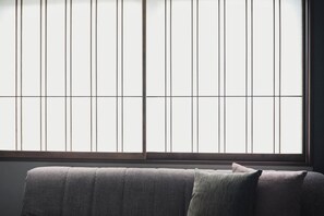 Ein Zimmer mit einem großen Fenster, einem Sofa und einem Kissen.