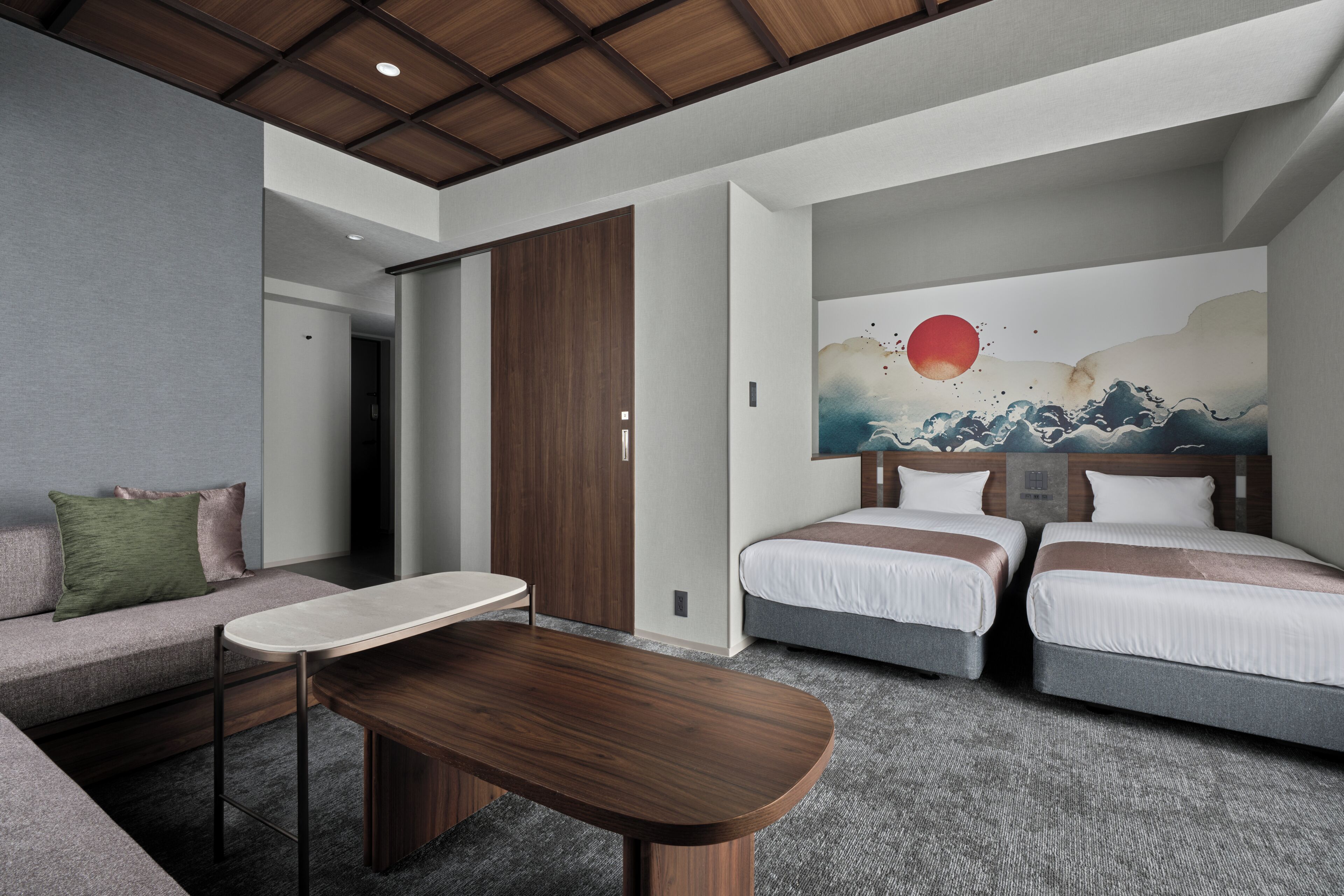 Una habitación de hotel moderna con un sofá, dos camas, un cuadro y una mesa de madera.