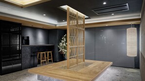 A modern interior with a central wooden platform, a bar area, and a decorative wall panel. - Premium MONday ASAKUSA I (Tokyo)
