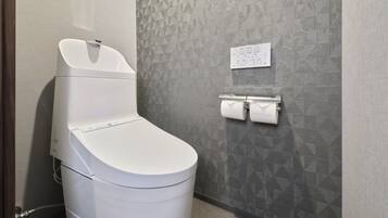 Een moderne badkamer met een wit toilet, een wanddispenser voor keukenpapier en een bedieningspaneel.
