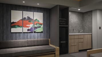 A modern room with a sofa, a kitchen area, and a wall-mounted artwork.