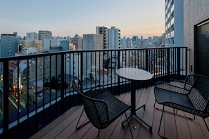 Un balcón con mesa y sillas, con vistas a un paisaje urbano con varios edificios.