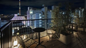 A rooftop terrace with a table and chairs, a view of a city skyline, and a tall tower in the distance. - Premium MONday ASAKUSA I (Tokyo)