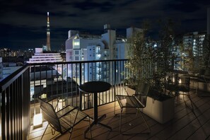 A rooftop terrace with a table and chairs, a view of a city skyline, and a tall tower in the distance. - Premium MONday ASAKUSA I (Tokyo)