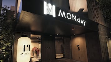 Un edificio moderno con un llamativo letrero 'MONday', una planta grande en maceta y una pared texturizada.