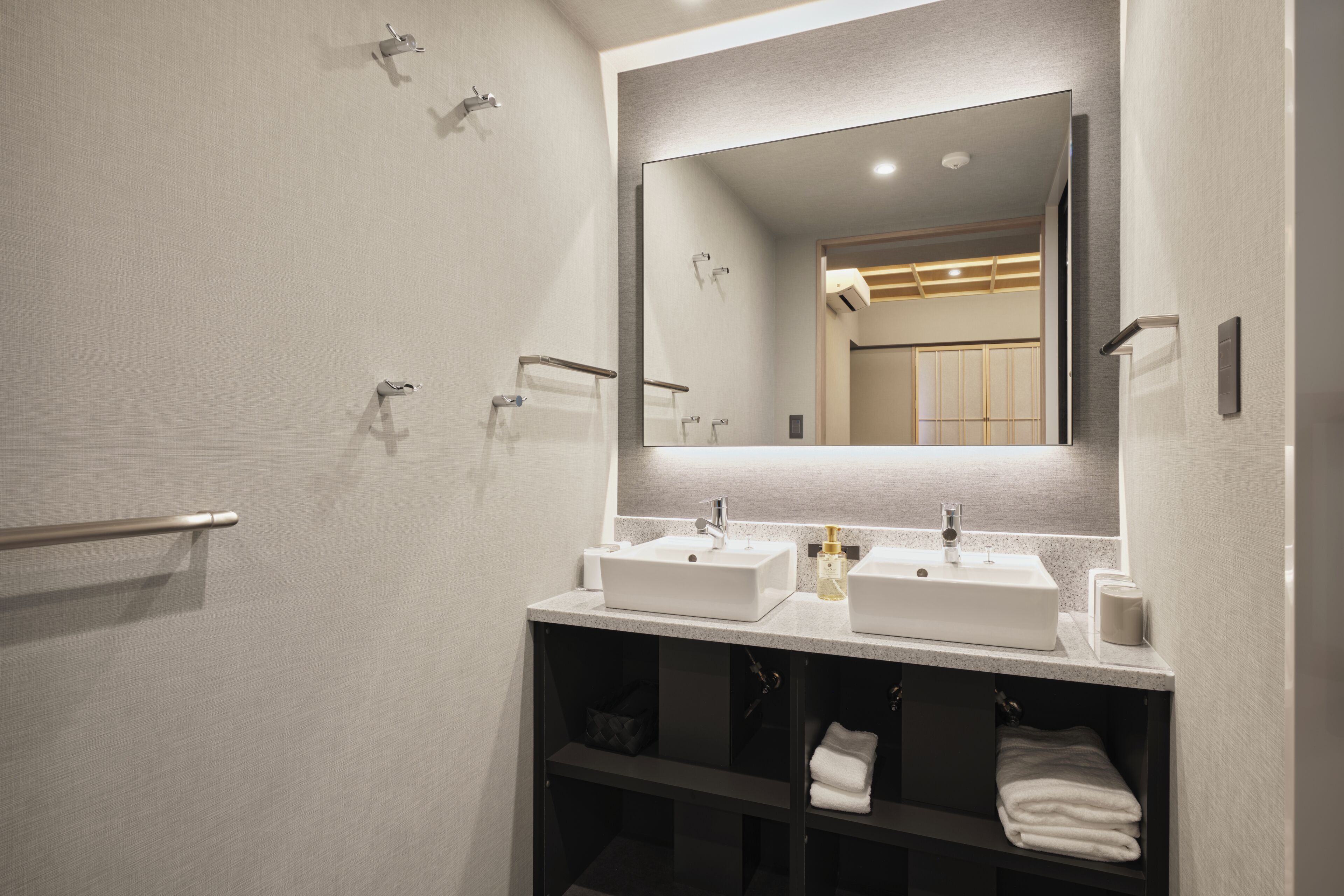 A modern bathroom with two sinks, a large mirror, and a towel rack.