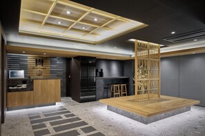 Un interior moderno con mostrador de recepción, zona de bar y asientos.
