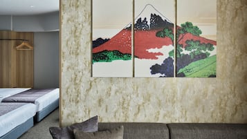 A room with a bed, a sofa, and a wall-mounted artwork depicting a mountain landscape.