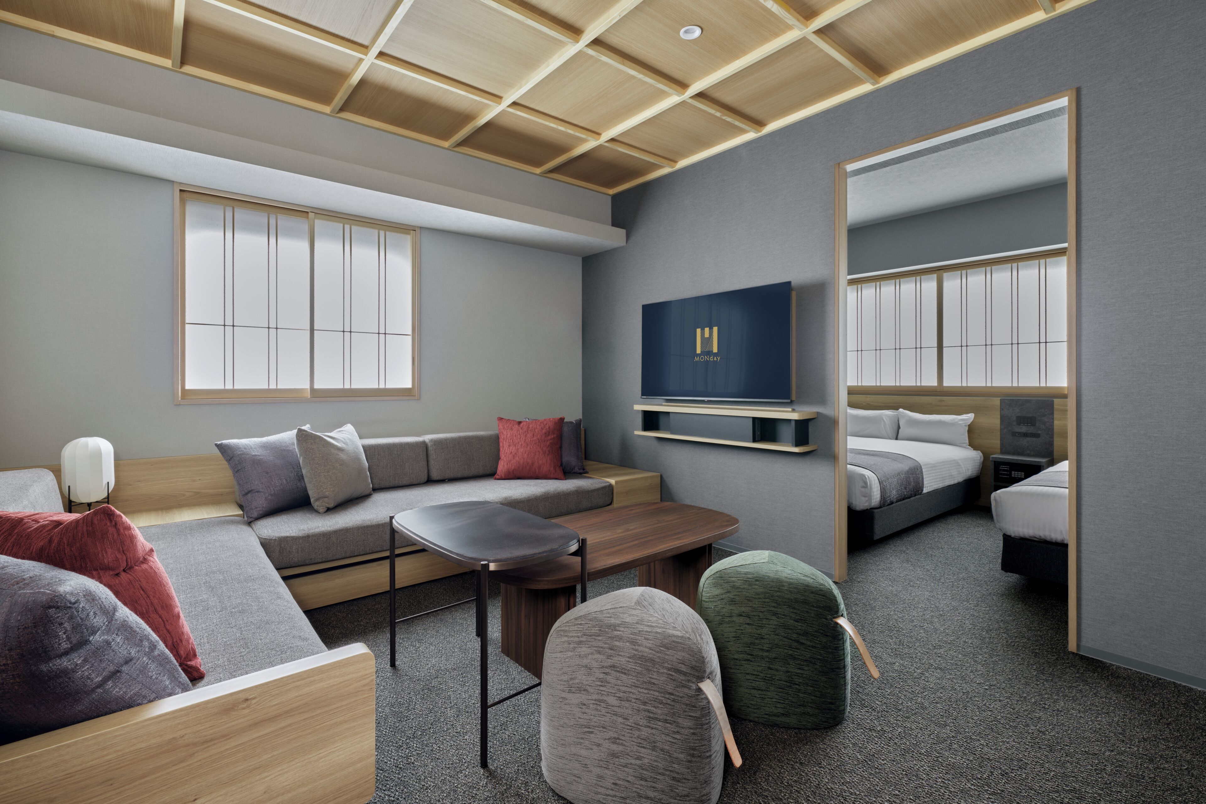 Una habitación de hotel moderna con sofá, una mesita, una silla, cama, televisión y espejo.