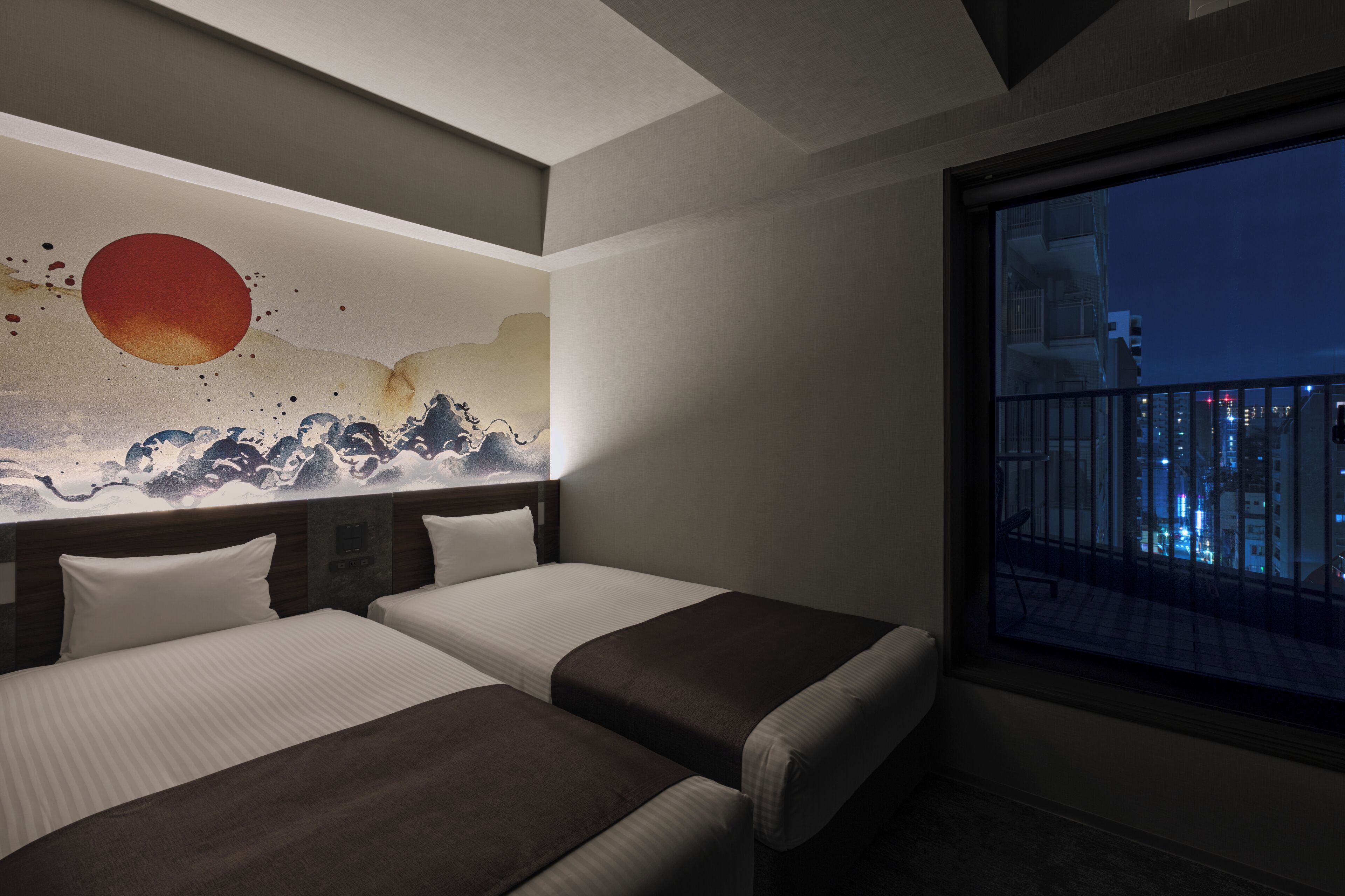 Une chambre d’hôtel avec deux lits, une grande fenêtre donnant sur la ville et une fresque murale.