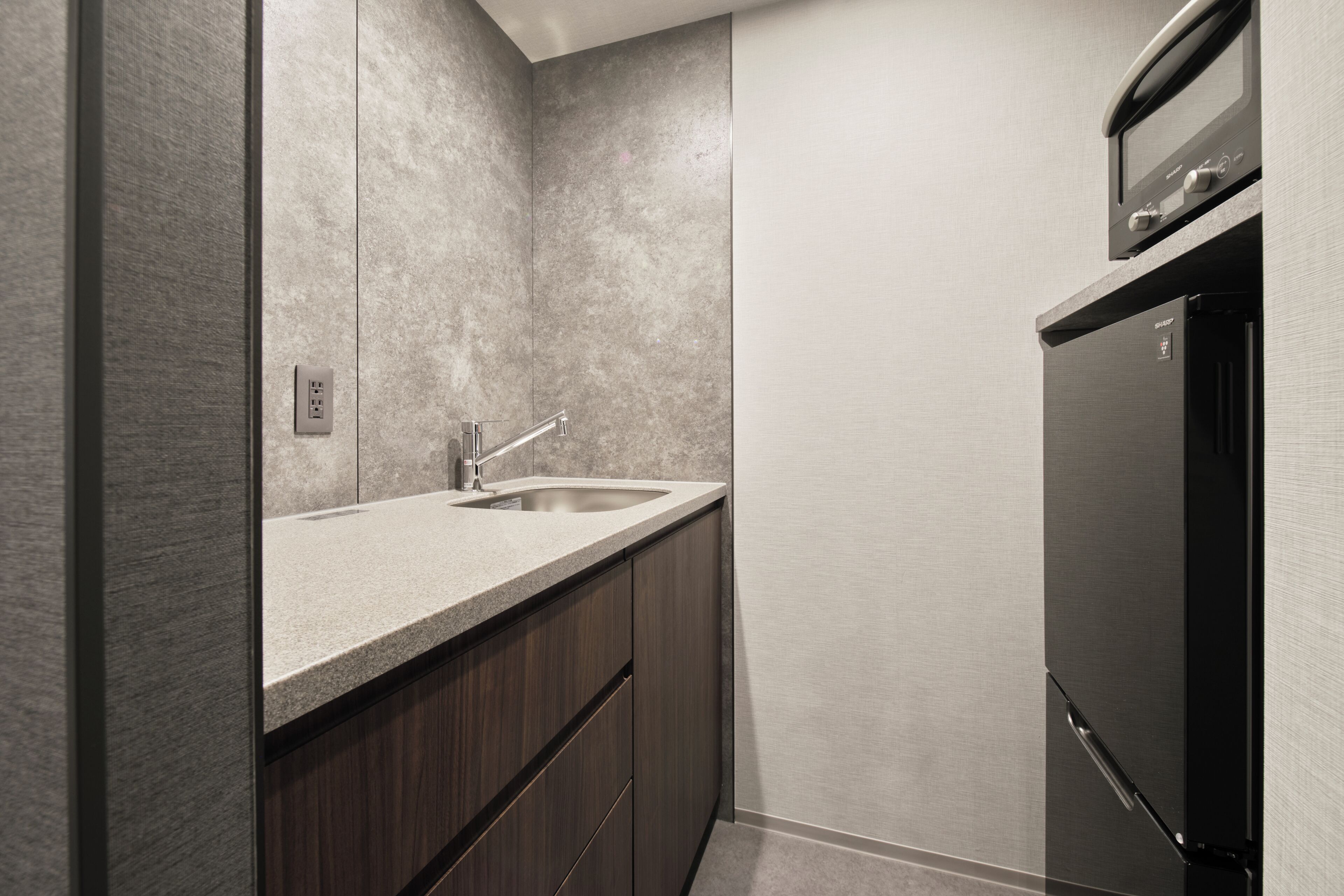 A modern kitchen with a built-in sink, dark wooden cabinets, and a black refrigerator.