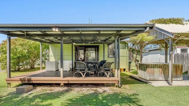 Un espace extérieur abrité avec une table et des chaises, une cour clôturée et une maison en arrière-plan.