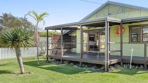 Une maison de plain-pied avec un porche couvert, une petite terrasse et une porte d’entrée bien visible.