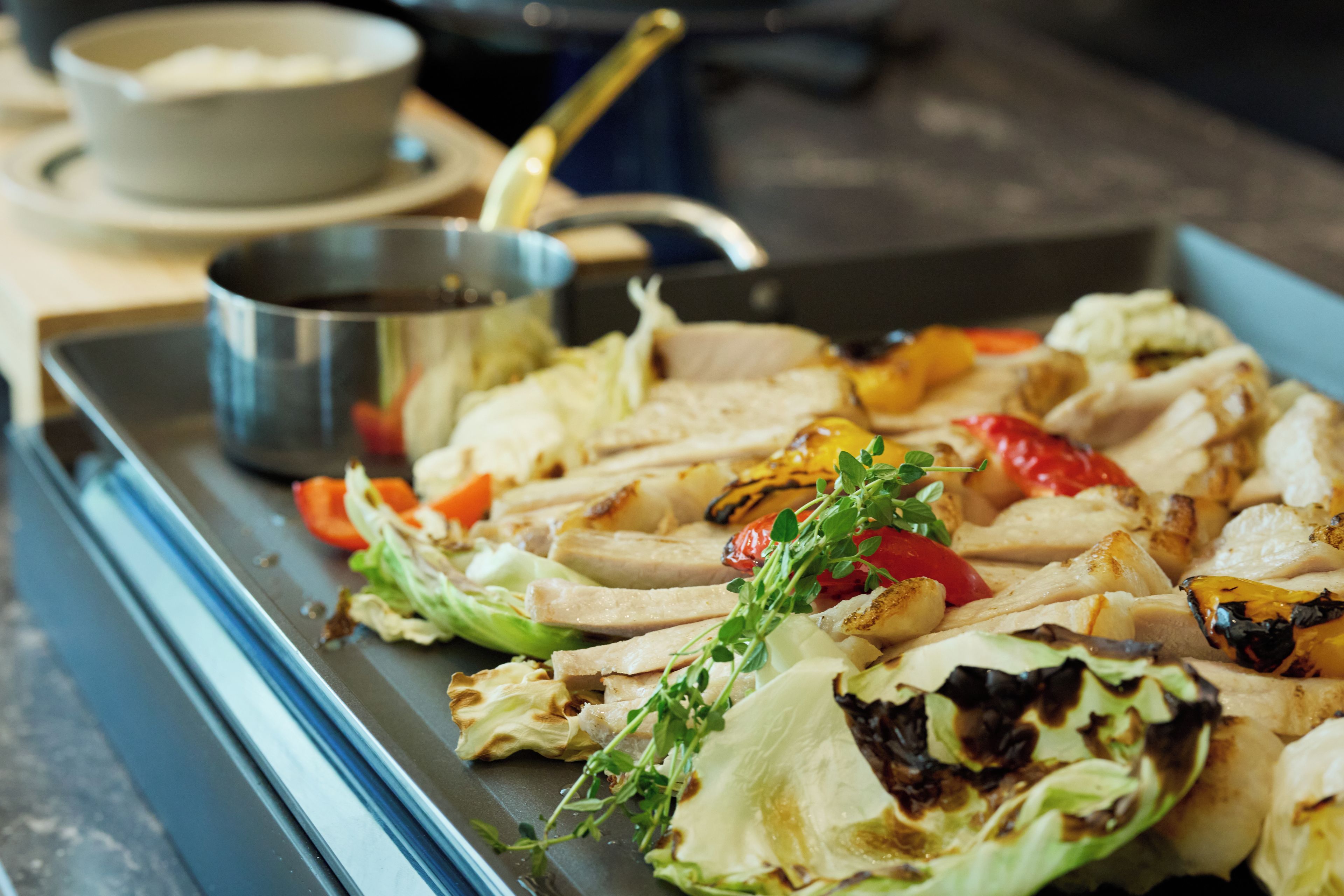 A tray of grilled chicken and vegetables on a table.