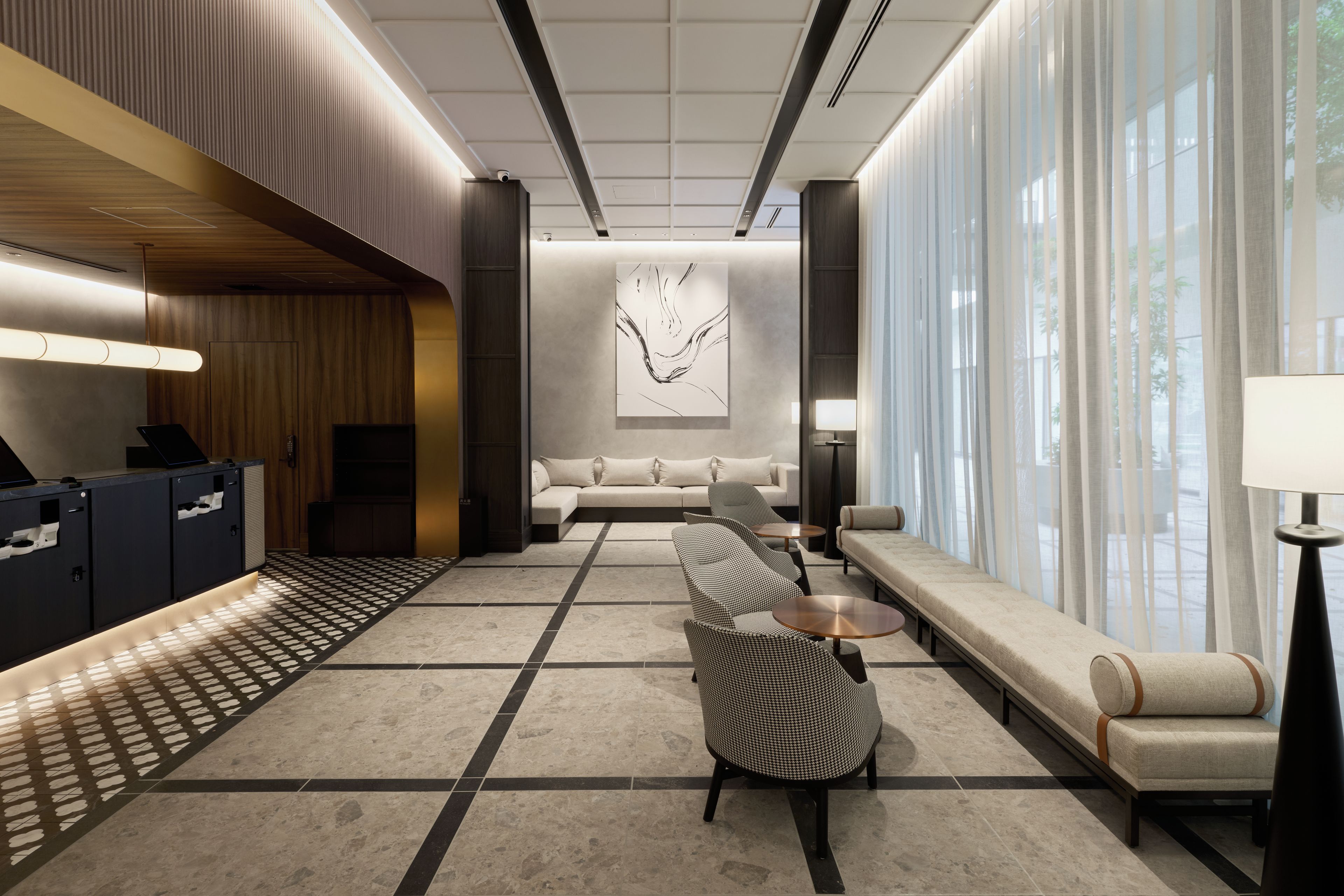 A modern hotel lobby with a reception desk, seating area, and a large abstract painting.