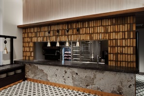 Una cocina con encimera de mármol, pared de paneles de madera y lámparas colgantes.