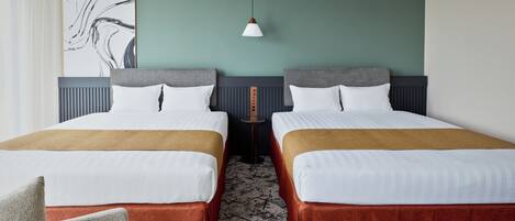 A hotel room with two beds, a wall-mounted artwork, a pendant light, and a patterned carpet.