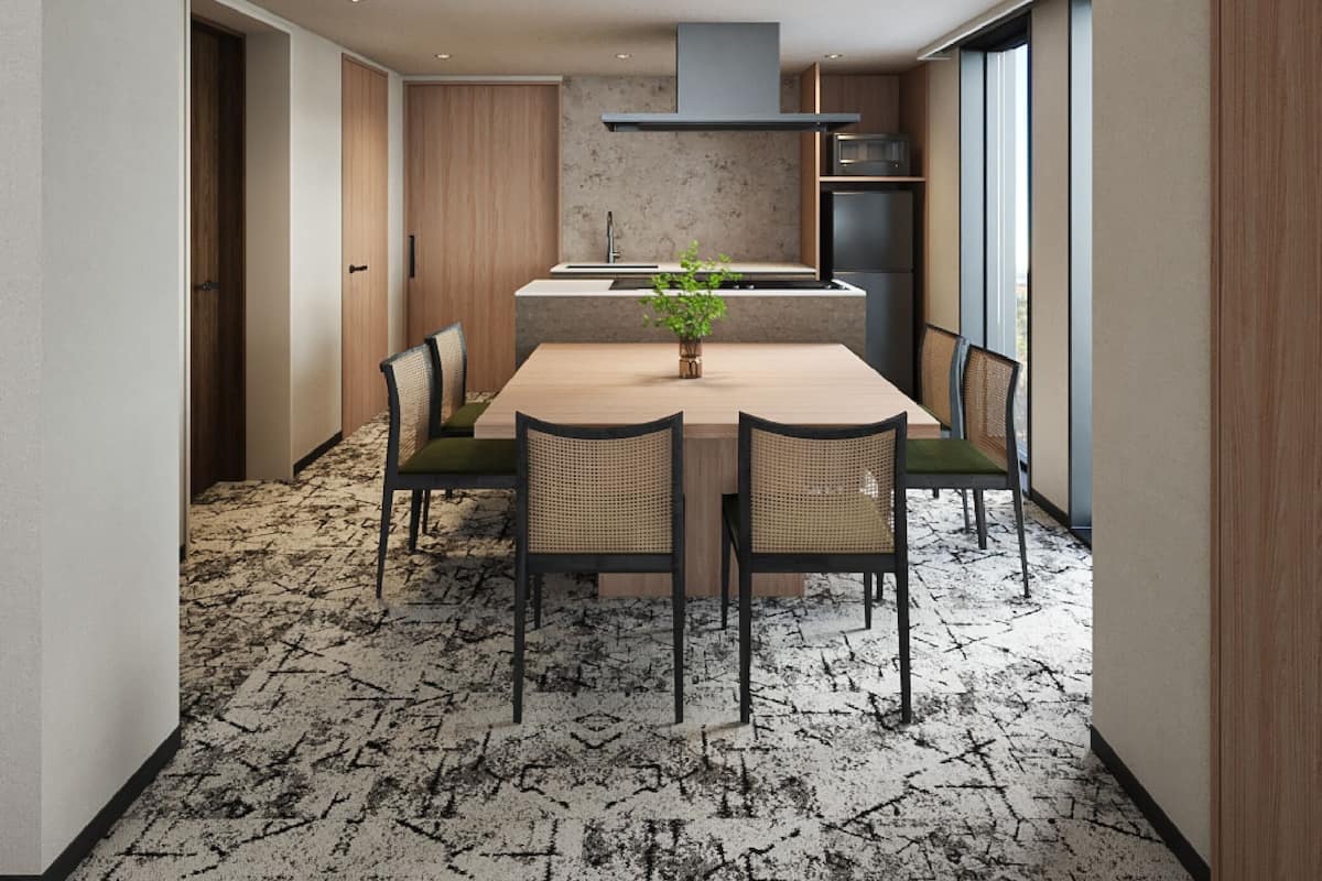 Una cocina moderna con una isla central, electrodomésticos integrados y un comedor con sillas y una mesa.