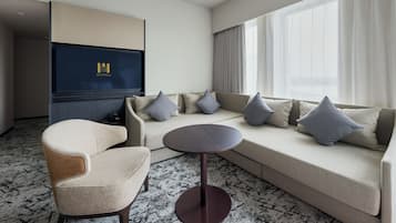 A hotel room with a sofa, armchair, and a small round table.