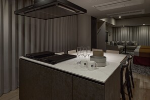 A modern kitchen with a built-in stove, a dining area with a sofa and table, and a living room with a couch and curtains. - Premium hotel MONday MAIHAMA VIEW II (Tokyo)