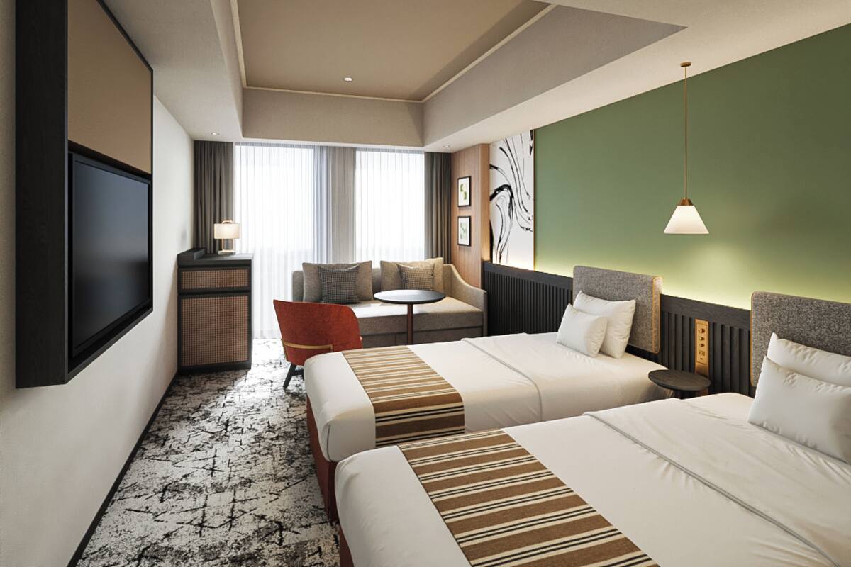 Habitación de hotel con dos camas, un sofá, un televisor, una mesita y una lámpara.
