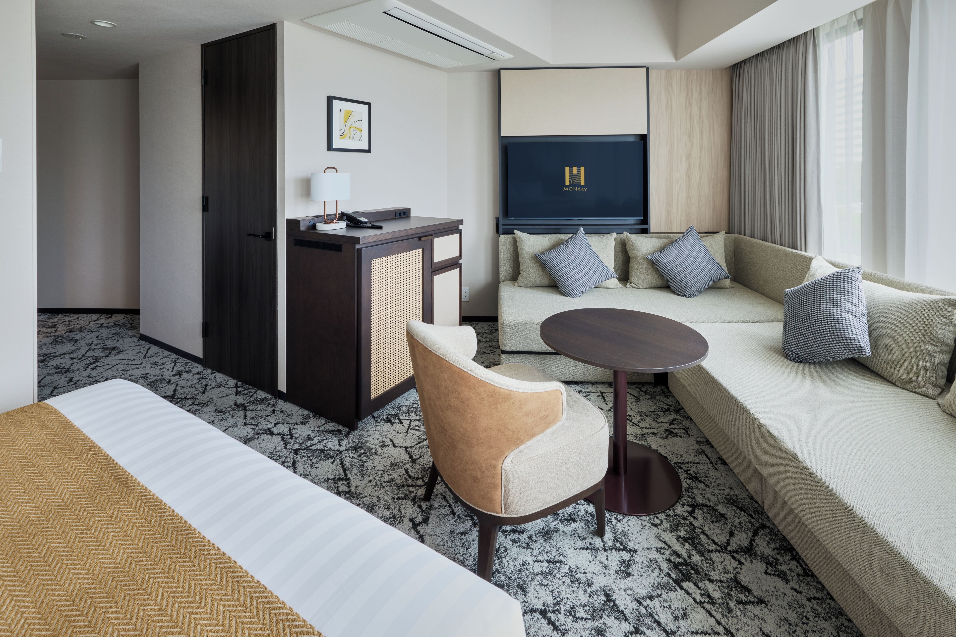 A hotel room with a bed, a sofa, a desk, and a chair.