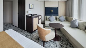 A hotel room with a bed, a sofa, a desk, and a chair.