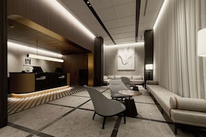 A modern lobby with a reception desk, seating area, and a large abstract artwork on the wall.