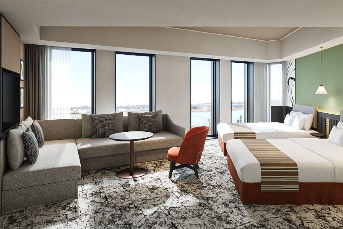Habitación de hotel con sofá, una mesita redonda, una cama individual y otra cama.