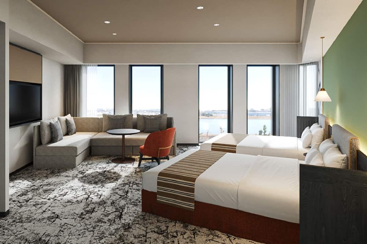 Una habitación de hotel con una cama grande, un sofá, una mesita y un televisor.