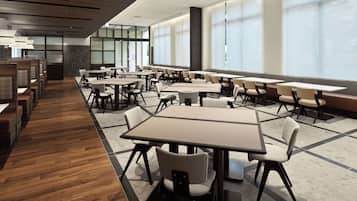 A modern conference room with multiple tables and chairs, large windows, and a wooden floor.