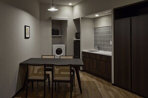 Eine moderne Küche mit integriertem Waschmaschine, einer Essecke mit Tisch und Stühlen sowie einem dunklen Holzschrank.