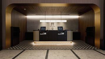 A reception desk with a modern design, a logo above it, and a patterned floor.