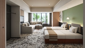 Una habitación de hotel moderna con sofá, dos camas, televisor y ventanas amplias.