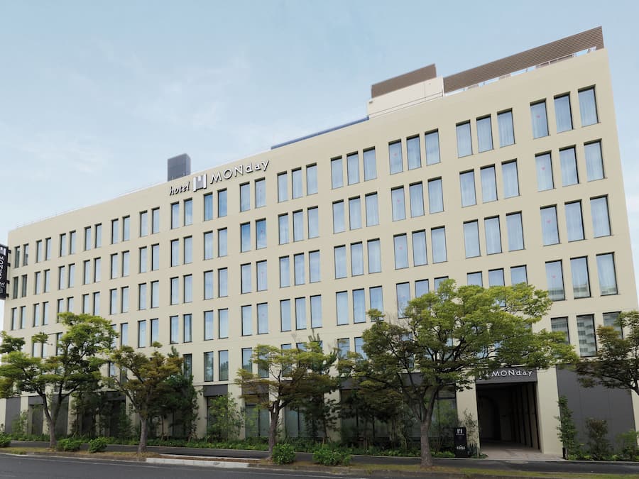 Un edificio moderno de hotel con fachada plana, múltiples ventanas y un cartel que indica que es el hotel MONday.