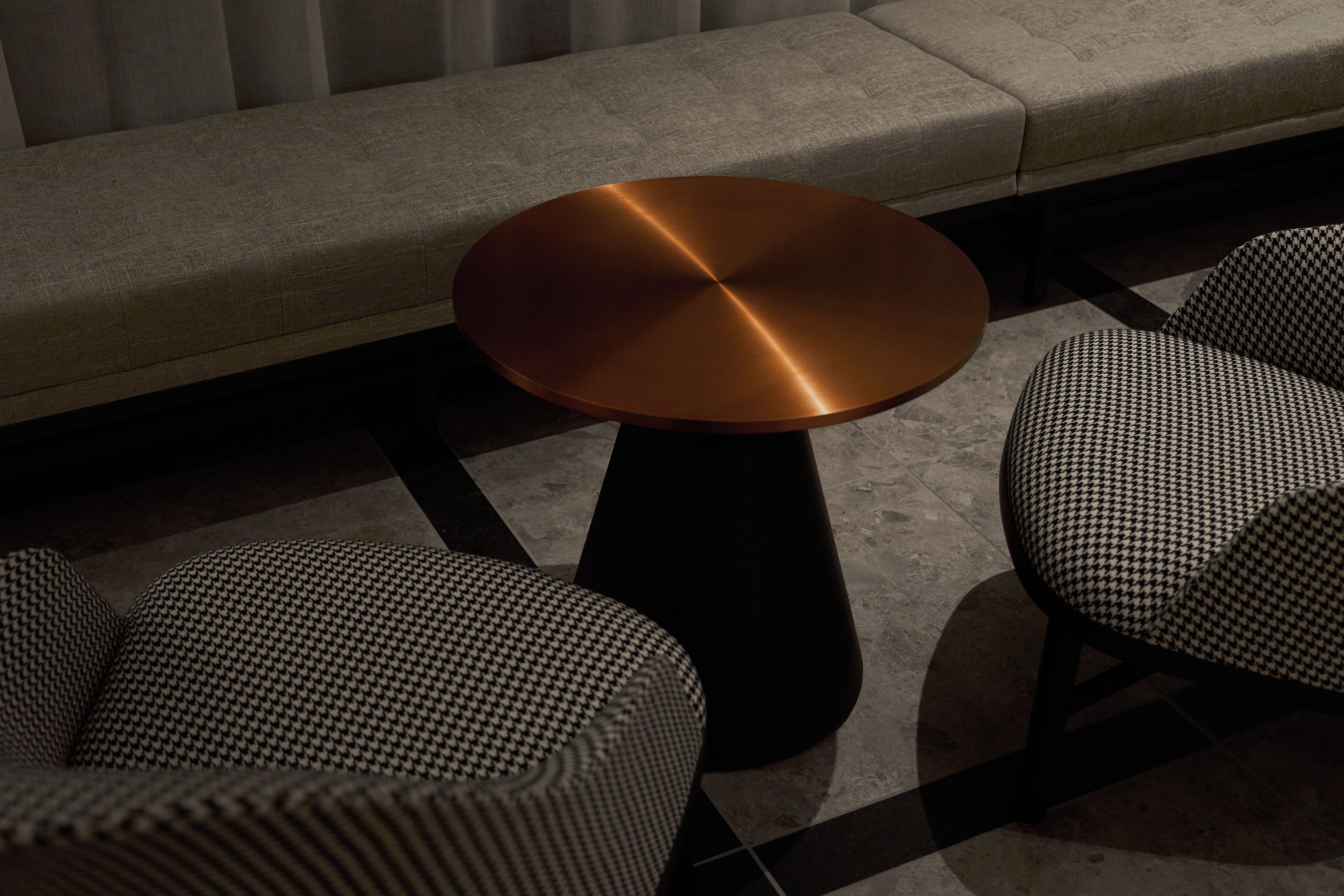 A modern seating area with a round table and two patterned chairs.