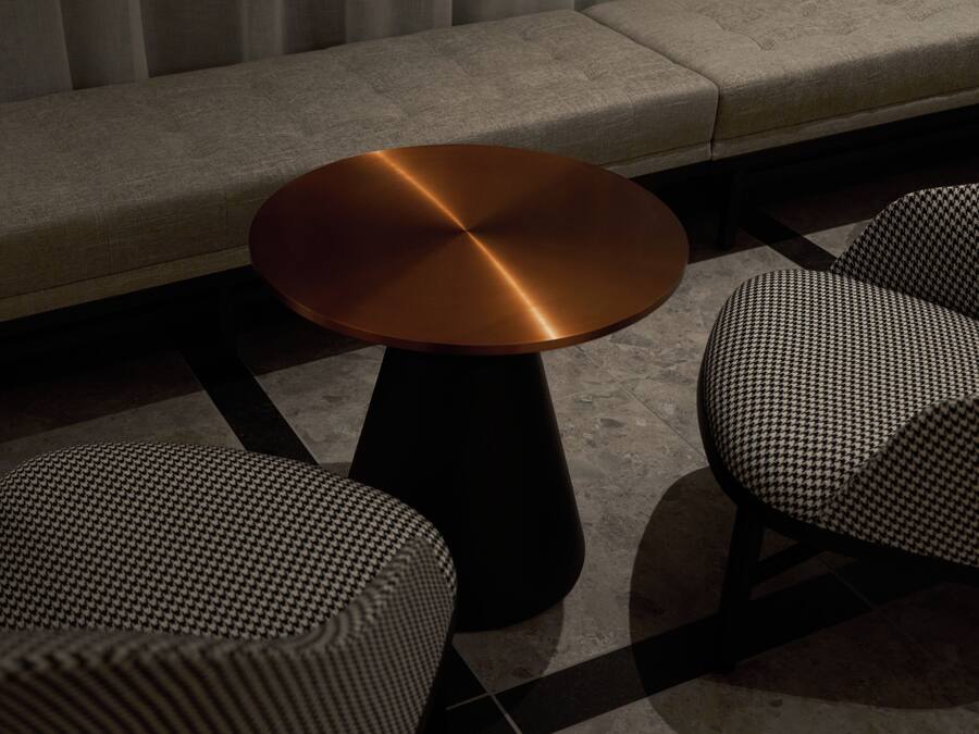 A modern seating area with a round table and two patterned chairs.