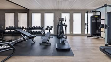 Un gimnasio con equipo de ejercicio, bancos y mancuernas.