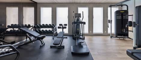 Un gimnasio con equipo de ejercicio, bancos y mancuernas.
