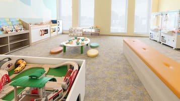 Ein Kinderspielzimmer mit einer Modelleisenbahn, Spielzeugtischen und Stauraumeinheiten.