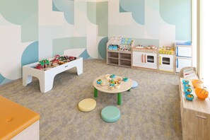 Ein Kinderzimmer mit Modelleisenbahn, Spielzeugtisch und Bücherregal.