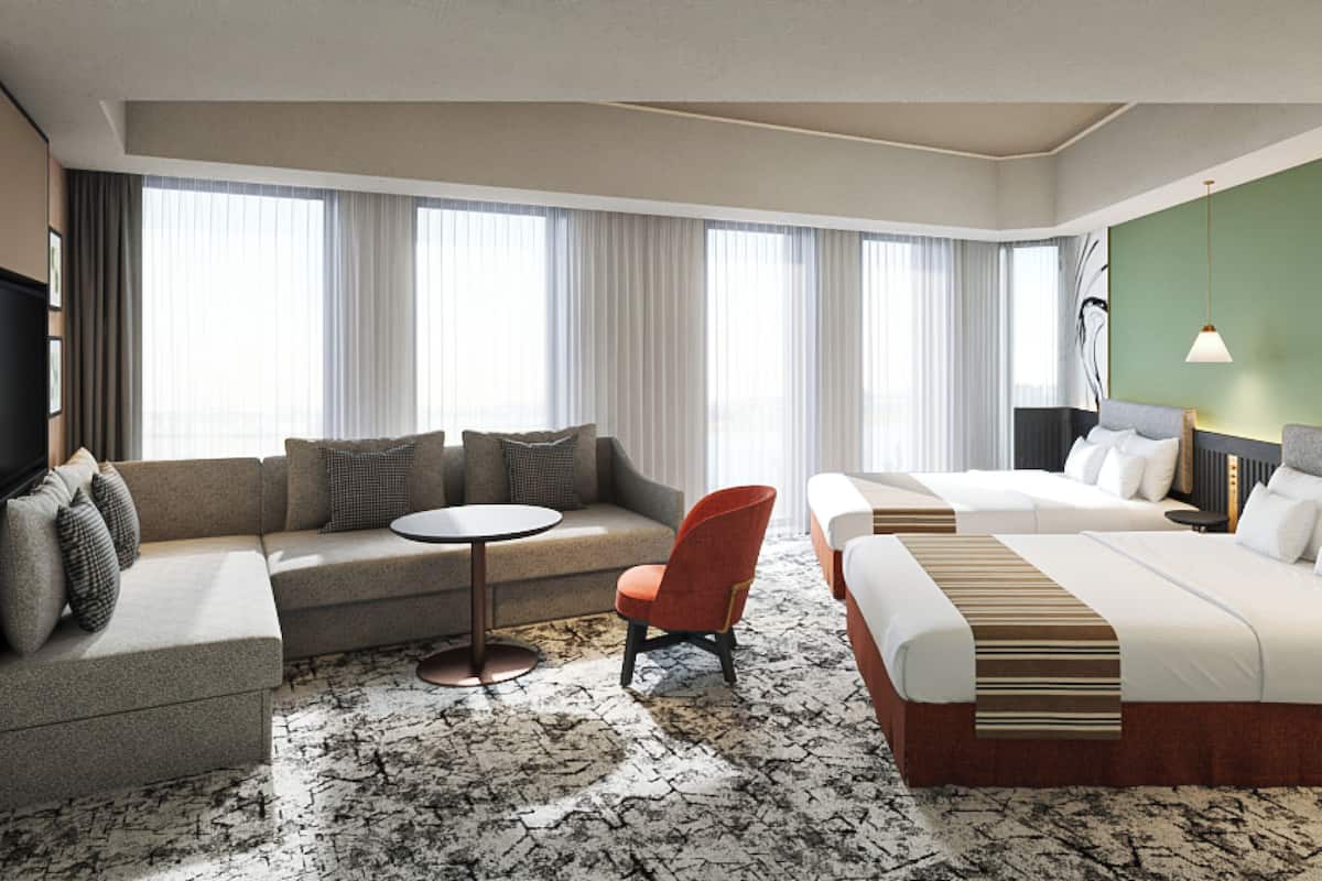 Una habitación de hotel con un sofá, una mesa redonda, una cama individual y una cama doble.