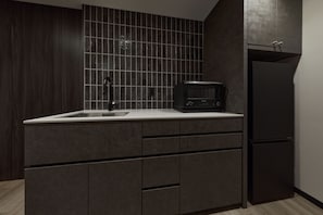 Una cocina moderna con armarios oscuros, una encimera blanca, una cafetera y un refrigerador empotrado.