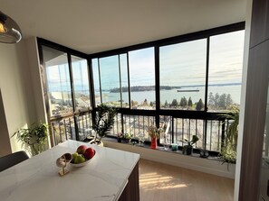 Una habitación moderna con un ventanal grande que da a un cuerpo de agua y un paisaje urbano.