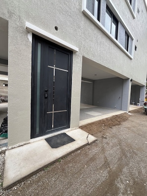 A building with a black door, a concrete entrance, and a paved driveway.