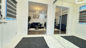 Um interior moderno com um sofá azul escuro, uma mesa de centro de vidro e uma luminária decorativa.