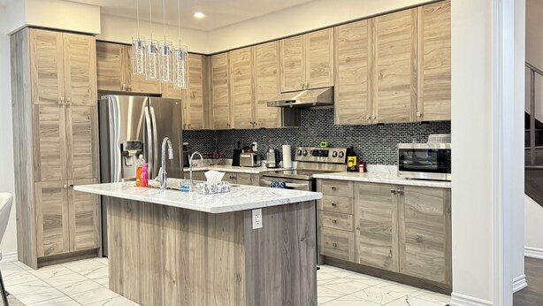 Uma cozinha moderna com armários de madeira, bancada de mármore, eletrodomésticos de aço inoxidável e painel de backsplash em preto e branco.