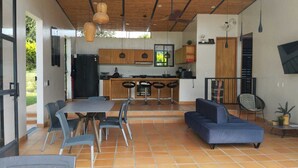 An open-plan living and dining area with a kitchen, a blue sofa, and a dining table with chairs. - Casa Campestre San Joaquin La Mesa (La Mesa)