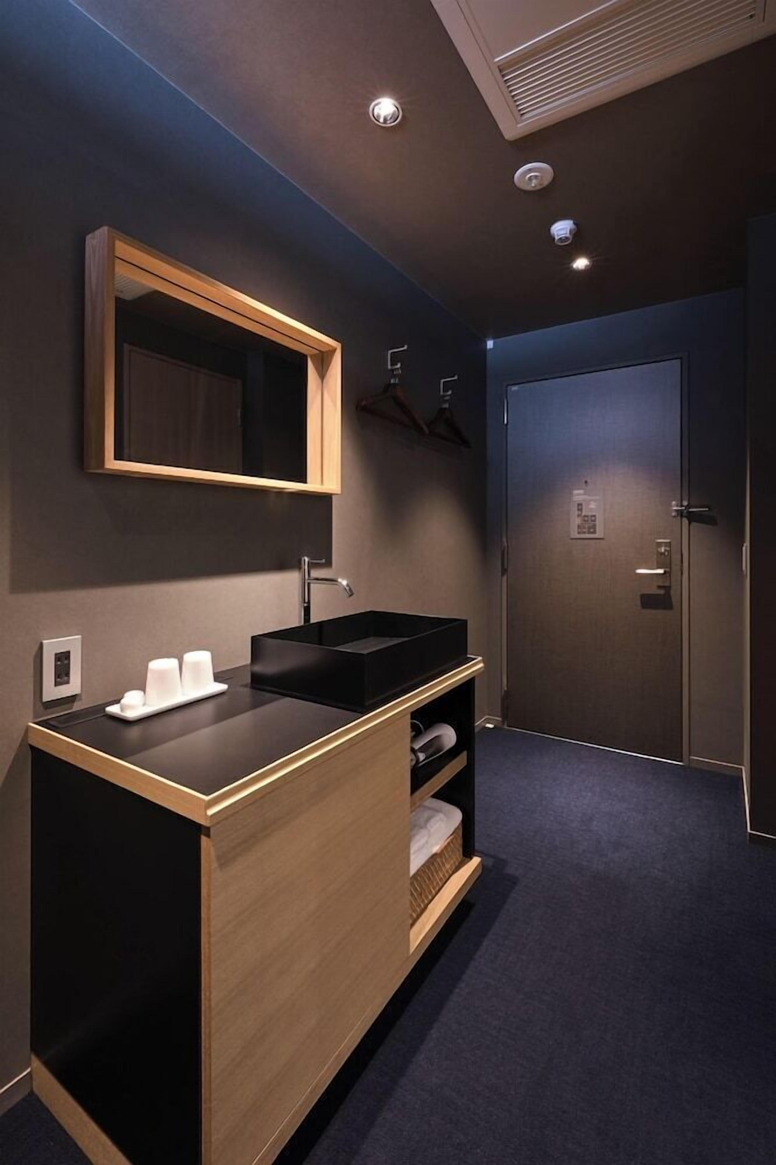 A modern bathroom with a black sink, wooden vanity, and a mirror.